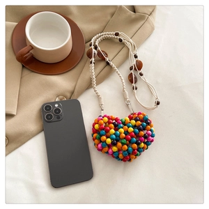 Detailed view of handmade colorful beaded heart crossbody bag with woven cotton strap