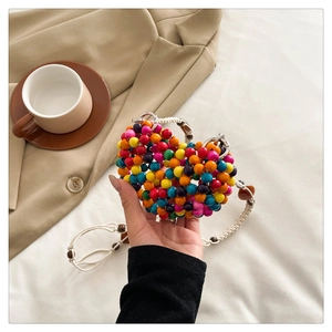 Detail of colorful wooden bead woven heart bag with white braided shoulder strap