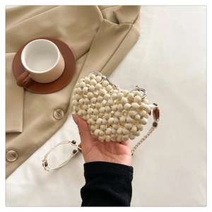 Detailed shot of a beige beaded crossbody bag with elegant amber-colored accents
