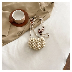 Detail of cream heart-shaped beaded mini bag with amber beads and woven strap
