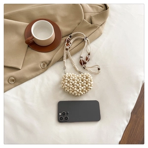 Mini heart-shaped beaded crochet bag in cream white with phone for size reference