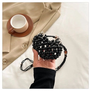 Detail of a handmade black heart-shaped beaded mini bag with silver rings and cord strap