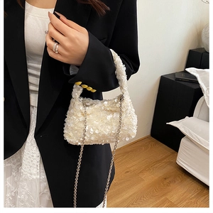 Detail of cream sequin mini bag with silver chain strap worn with a black blazer