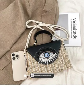 Détail du sac en paille tissé à la main avec broderie œil et breloques en perles