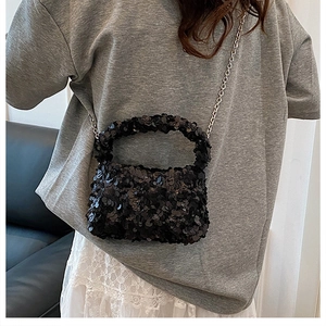 Detail shot of shimmering black sequins and silver chain strap on a small crossbody bag