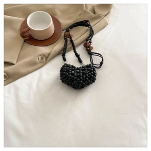 Detailed view of handmade black beaded heart-shaped mini bag with amber bead strap