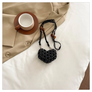 Detail of a handmade black beaded heart bag with amber accents and metal buckles