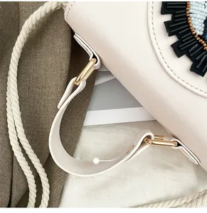 Détail de broderie en perles sur sac en cuir crème avec anse en corde tressée