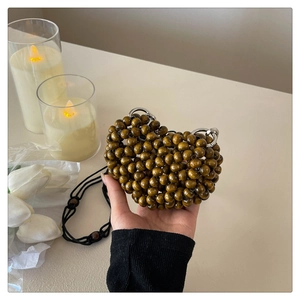 Close-up of heart-shaped olive green wooden beaded bag with silver hardware