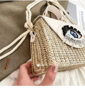 Détail du sac en paille avec rabat en cuir, œil en paillettes et bandoulière en coton