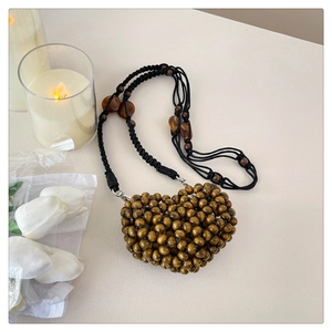 Detailed view of heart-shaped woven handbag made of dark brown wooden beads