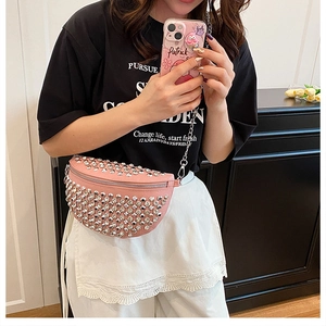 Sac bandoulière en similicuir rose avec clous argentés et chaîne porté par un mannequin
