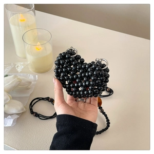 Detail of heart-shaped black beaded mini bag with silver rings and crossbody strap