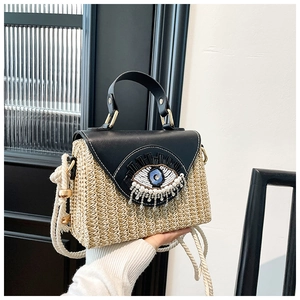 Détail du sac à main en paille tressée avec motif œil perlé et bandoulière en corde
