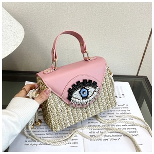Détail du sac en paille tissé avec rabat en cuir rose et décoration d'œil en paillettes