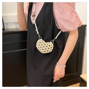 Close-up of heart-shaped woven beaded crossbody bag with chunky strap on model