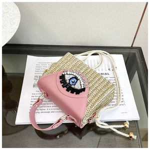 Détail du sac tissé rose avec design yeux perlé et bandoulière en corde de coton