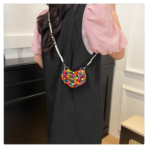Detail of colorful handmade beaded heart-shaped mini crossbody bag with woven strap