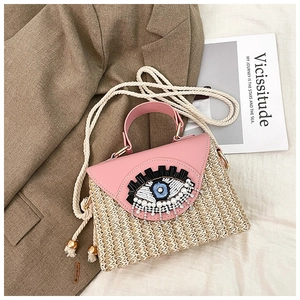 Détail du rabat en cuir rose avec broderie œil et perles sur le sac en paille tissée
