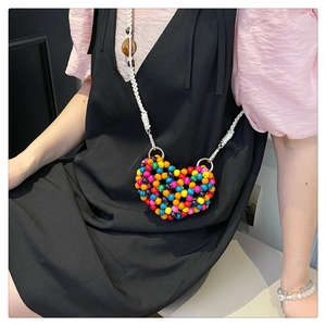 Detail of colorful heart-shaped beaded mini bag with white woven shoulder strap