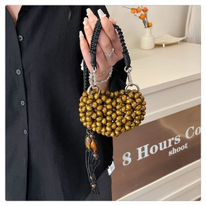 Detail view of heart-shaped beaded handbag with light brown wood beads and black handle