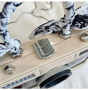 Macro shot of the camera-shaped bag featuring a silk-wrapped handle and silver metal clasp