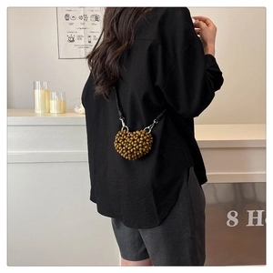 Detail view of heart-shaped woven wooden bead crossbody bag with black braided strap