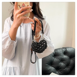 Detailed view of handmade black beaded heart-shaped handbag held by a model