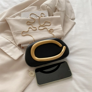 Bolso de mano negro con forma de guijarro, asa en C dorada y cadena metálica fina