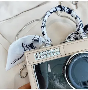 Close-up of camera-shaped bag with rhinestone accents and silk scarf wrapped handle