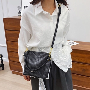 Fashionable black woven crossbody bucket bag with gold hardware and adjustable strap