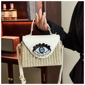 Détail du sac boîte en paille avec patch œil pailleté et rabat en cuir blanc