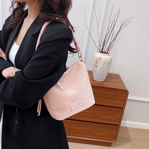 Chic pink woven bucket bag with shoulder strap shown in a stylish home setting