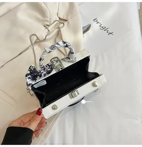 Detail of white PVC box bag with printed silk scarf handle and metal chain strap
