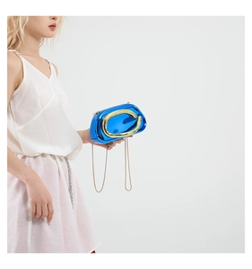 Details der blauen Metallic-Clutch mit goldenem Rundgriff und schmalem Kettenriemen