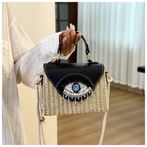 Détail d'un sac en paille tissé main avec œil en sequins et pampilles de perles