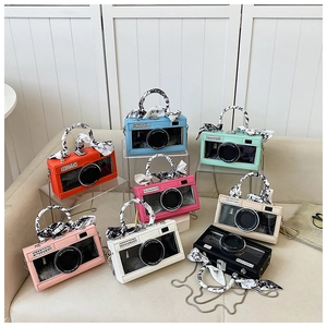 Detail of camera-shaped crossbody bags in eight colors with silk scarves and metal chains