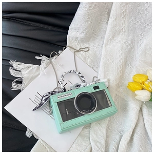 Detail of mint green camera-shaped bag with a silk scarf handle and silver chain strap