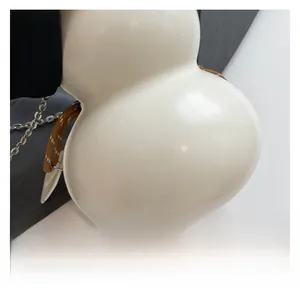 Dettaglio ravvicinato della borsa color crema a forma di zucca con trama in pelle
