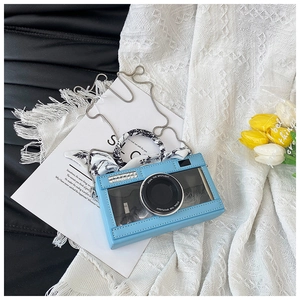 Detail of blue camera-shaped bag with transparent window and decorative silk scarf