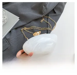 Detail of white marble acrylic clutch with pebble clasp and gold chain strap