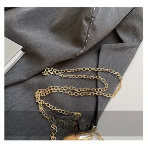 Close-up of shiny gold metal chain strap on grey fabric for women's acrylic handbag