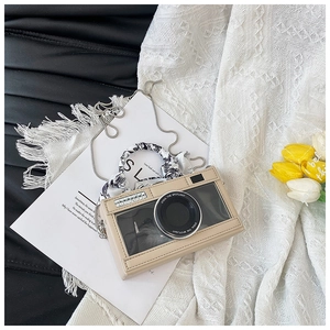 Detail of camera-shaped crossbody bag featuring transparent window and scarf-wrapped handle