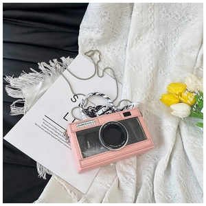 Detail of pink camera-shaped crossbody bag with rhinestone lens and silk-wrapped handle