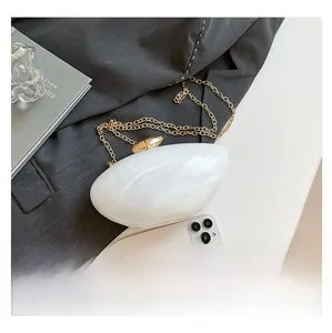 Detail of shell-shaped acrylic evening bag showing marble texture and gold chain