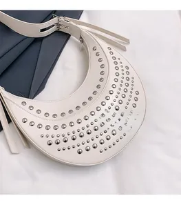 Détail du sac croissant crème avec rivets argentés décoratifs et large bandoulière