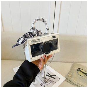 Detail of camera-shaped crossbody bag with diamond accents and silk scarf handle decor