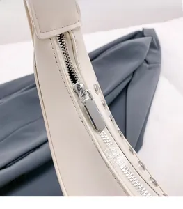 Détail de la fermeture éclair en métal argenté sur un sac à bandoulière clouté