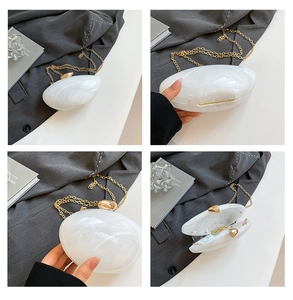 Detail view of white acrylic evening clutch with marble texture and gold chain strap
