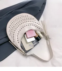Détail du sac croissant crème montrant l'intérieur spacieux et les rivets argentés